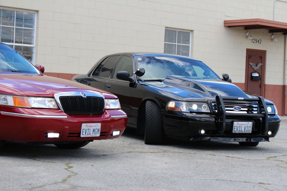 Maroon Mercury and black Crown Victoria with bull bar parked close, front clips
