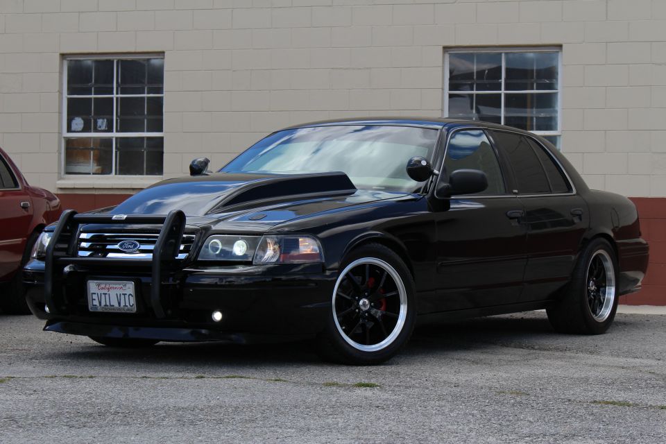 Lowered black Ford Crown Victoria with push bar and black wheels, plate EVIL VIC