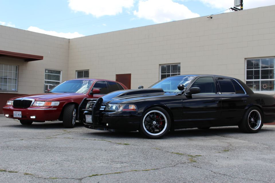 Dark red Mercury and black Ford Crown Victoria with push bar parked side by side