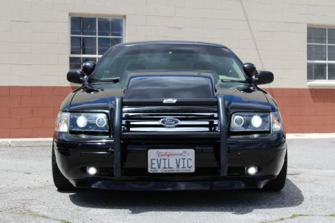 2003 Ford Crown Victoria - Front close-up of a black Ford Crown Victoria with a brush guard, halo headlights and a California 'EVIL VIC' plate.