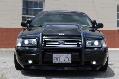 2003 Ford Crown Victoria - black Ford Crown Victoria photographed head-on, with a Ford grille badge, brush guard and 'EVIL VIC' California plate.