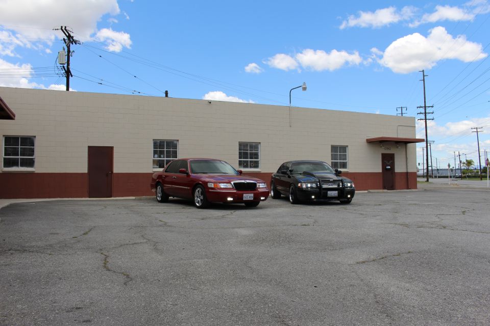 Three-quarter view of maroon Mercury and black sedan by a warehouse