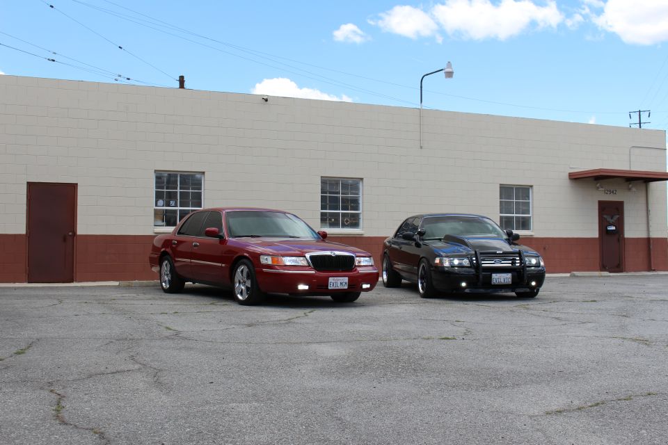 Maroon Mercury and black sedan parked at an angle on cracked asphalt