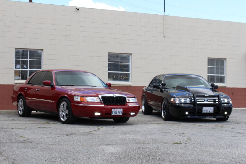 Maroon Mercury and black Ford with grille guard parked at an angle