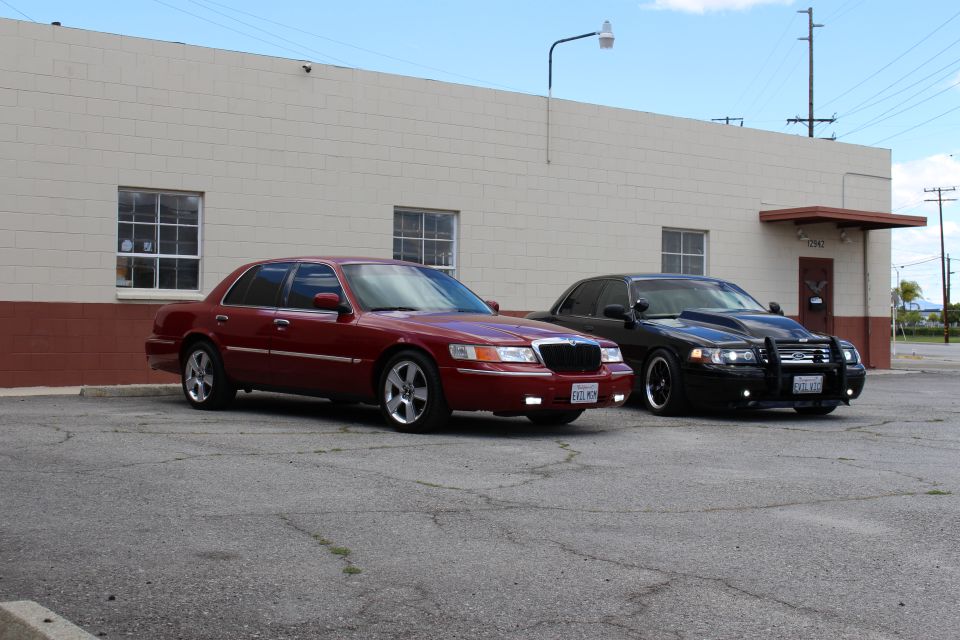Maroon Mercury and black Ford sedan parked at an angle in a wide lot