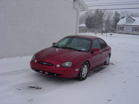 1998 Ford Taurus - Red 1998 Ford Taurus sits in a snowy driveway next to a building.