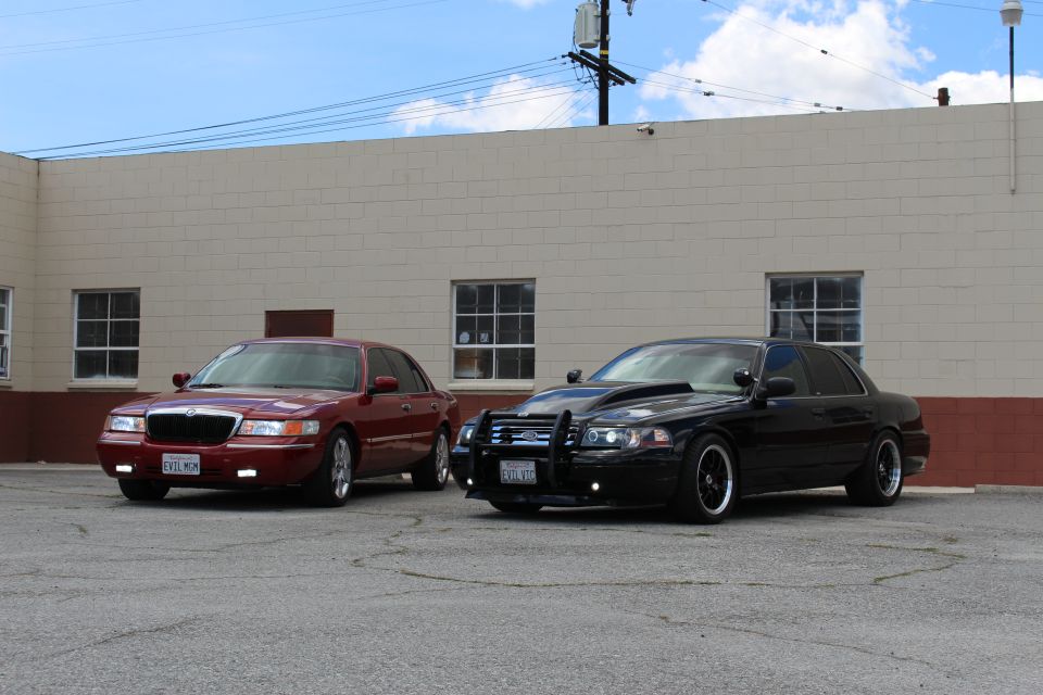Maroon Mercury and black Ford sedan parked front-side by a warehouse