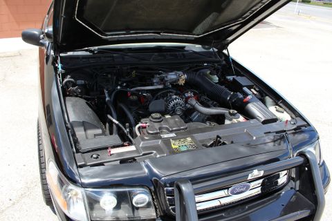 2003 Ford Crown Victoria - Under-hood view of a black Ford sedan showing the engine, air intake and a chrome-accented front brush guard.