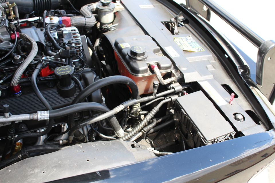 Engine bay detail showing coolant reservoir and fuse box of a black car
