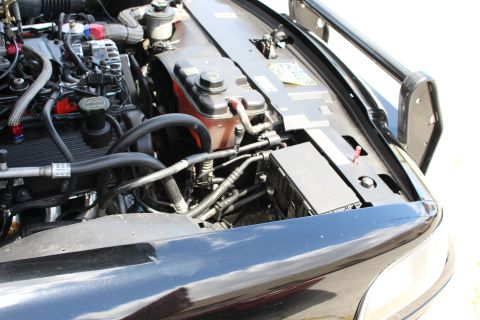 2003 Ford Crown Victoria - Side view of a black car's engine bay showing wiring, a coolant reservoir and a black fuse box near the fender.