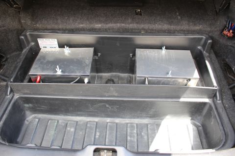 2003 Ford Crown Victoria - Close view of a trunk tray holding two aluminum battery boxes, marked with a Ford 'Police Trunk Pack' label.