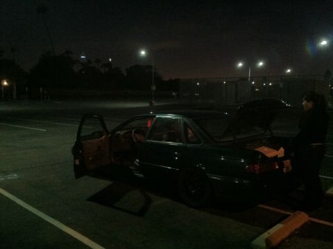 1995 Ford Taurus - A dark green sedan sits in a parking lot at night with its doors and trunk open.