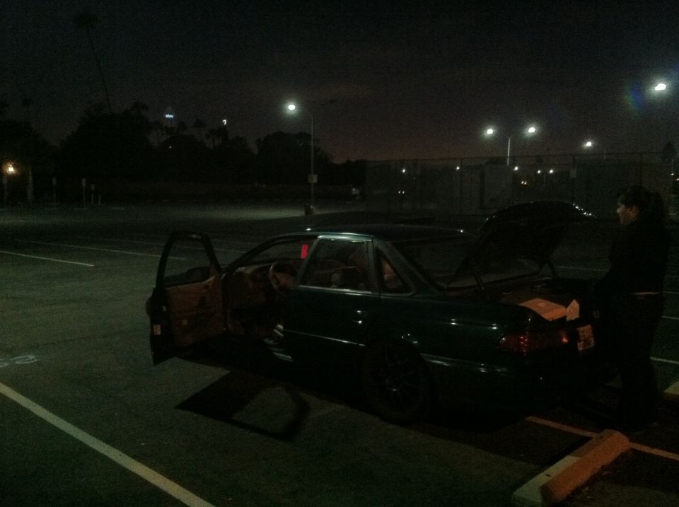 Dark green sedan with doors and trunk open at night