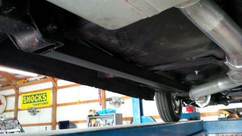 1963 Chevrolet Nova - Undercarriage view of a vehicle, including exhaust system and rear wheel, with a 'SHOCKS' sign in the background.