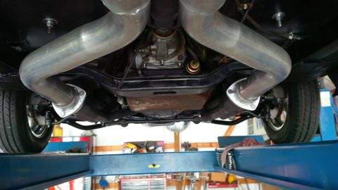 1963 Chevrolet Nova - The undercarriage of a vehicle is shown, a dual exhaust system and differential, supported by a car lift.