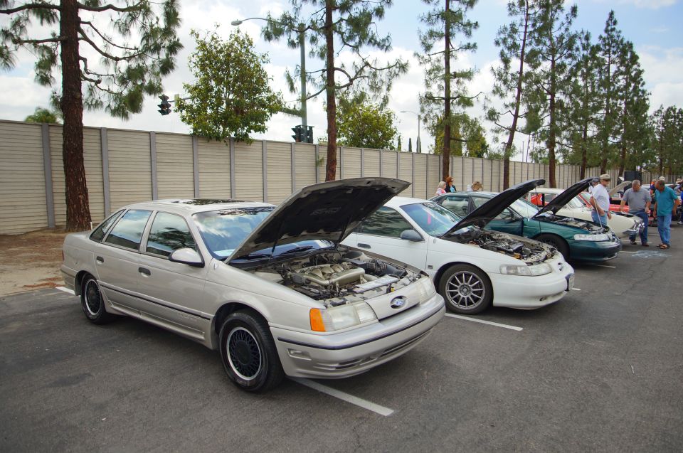 Silver sedan with hood open, showing engine. Black wheels, sunroof. Parked in a lot with other cars