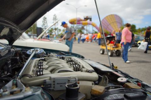 1995 Ford Taurus - A car show event with multiple vehicles and attendees milling about.