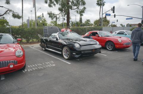 1995 Ford Taurus - Several Ford Thunderbirds are parked in a lot, including a black convertible with its top partially open.