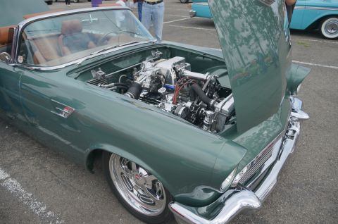 1995 Ford Taurus - A green convertible with its hood open, revealing a polished engine, sits in a parking lot.