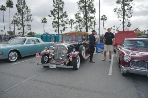 1995 Ford Taurus - A vintage convertible is parked at an outdoor event, with other classic cars and people around.