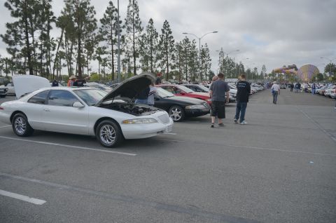1995 Ford Taurus - A white coupe, likely a 1996 model, is displayed with its hood open at a car show.