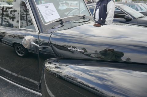 1995 Ford Taurus - A black Lincoln Continental is parked at an outdoor car show, with a document visible on its dashboard.