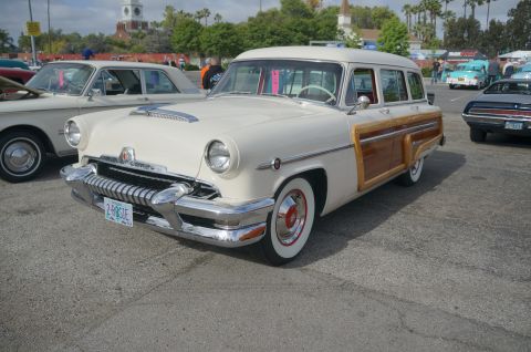1995 Ford Taurus - A cream 1954 Mercury station wagon with distinctive wood paneling is parked at a car show.