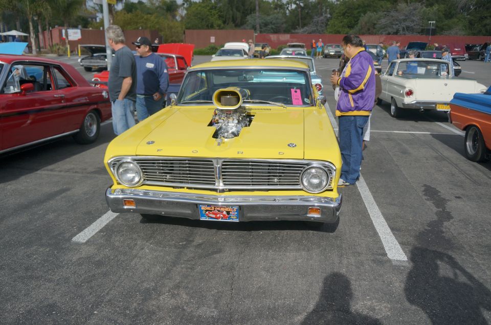 Yellow 1964 Ford Falcon with chrome grille, hood scoop, and a license plate reading 'Fabulous Fords Forever'