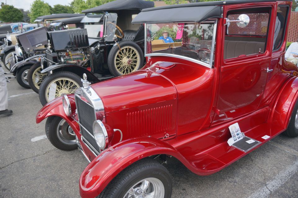 Red antique car parked in a row with other vintage vehicles