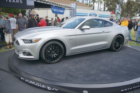 1995 Ford Taurus - A silver Ford Mustang is displayed at an outdoor car show, with spectators gathered around.