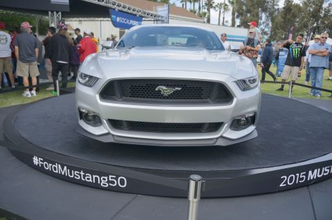 1995 Ford Taurus - A silver 2015 Ford Mustang is showcased on a display platform with event signage.