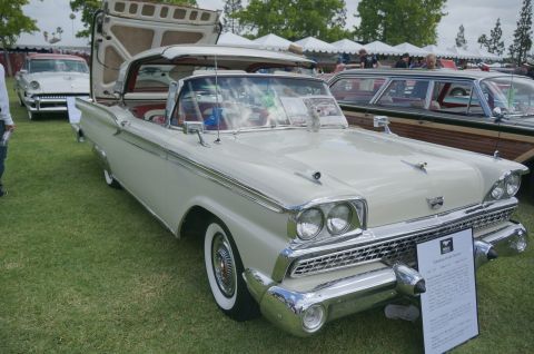 1995 Ford Taurus - A classic cream convertible with its hood and trunk open sits on display at a car show.