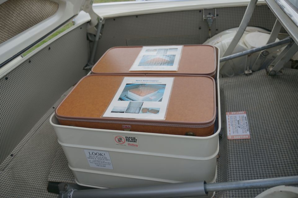 Trunk interior with two brown suitcases and caution labels