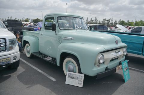 1995 Ford Taurus - Classic light blue 1956 Ford F-100 pickup truck at a car show, parked beside a modern white Ford F-150.