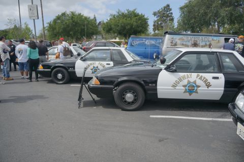 1995 Ford Taurus - Two Ford Mustang police cars are parked next to each other at an outdoor event.