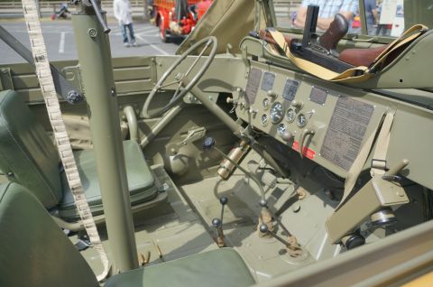 1995 Ford Taurus - The interior of an olive drab military vehicle shows a steering wheel, dashboard gauges, and several gear shifters.