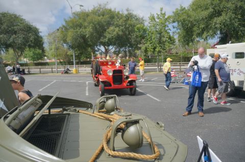 1995 Ford Taurus - A vintage red fire truck is parked in a lot with several people observing it.