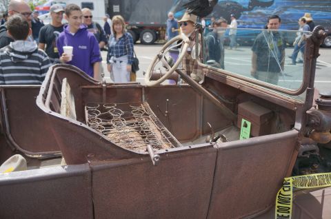 1995 Ford Taurus - An old, rusty car interior is viewed from the side, with people gathered around in the background.