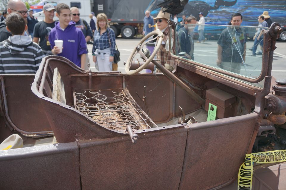 Rusty antique car interior with exposed springs on the seat, a steering wheel, and a windshield