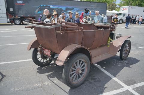 1995 Ford Taurus - This weathered antique car, seen from the rear, features spoked wheels and a wooden frame for its top.
