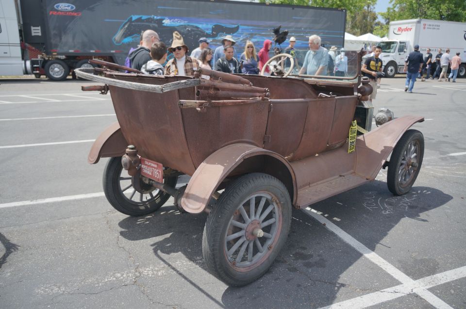 Rusty antique car with wooden top and spoked wheels, rear view