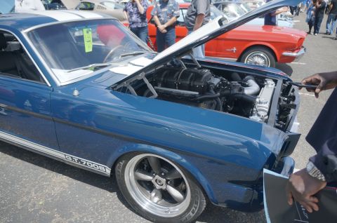 1995 Ford Taurus - Classic blue car with hood open at a car show, showing its engine and supercharger.