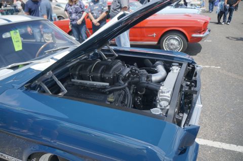 1995 Ford Taurus - A blue classic car's engine bay is open, revealing a supercharged engine. Another classic car is parked behind it.