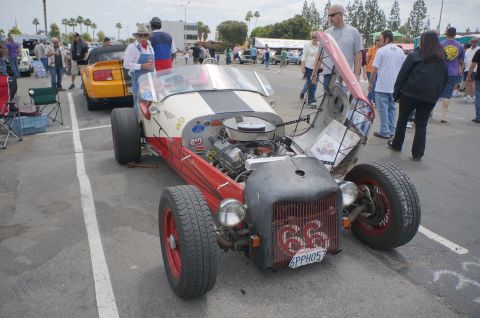 1995 Ford Taurus - A custom hot rod with its hood open, revealing the engine, at an outdoor car show.