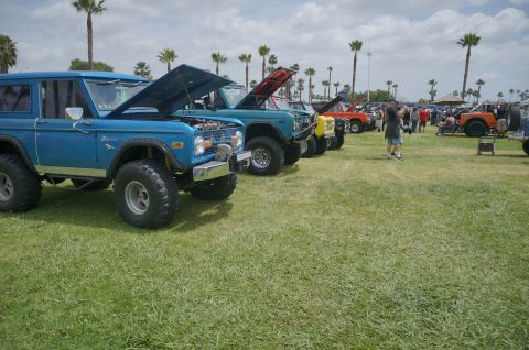 1995 Ford Taurus - A line of classic Ford Broncos are displayed on a grassy field under a cloudy sky.