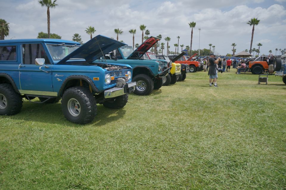 Blue 1977 Ford Bronco with hood open, parked in a line with other vehicles