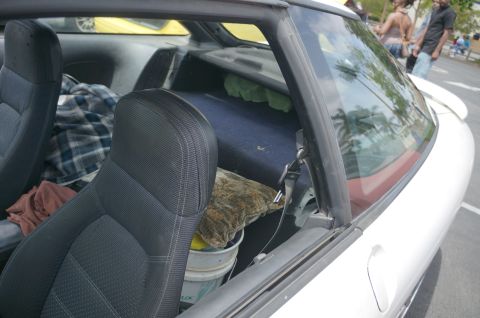 1995 Ford Taurus - The interior of a white car is visible, with seats and items stored in the back.