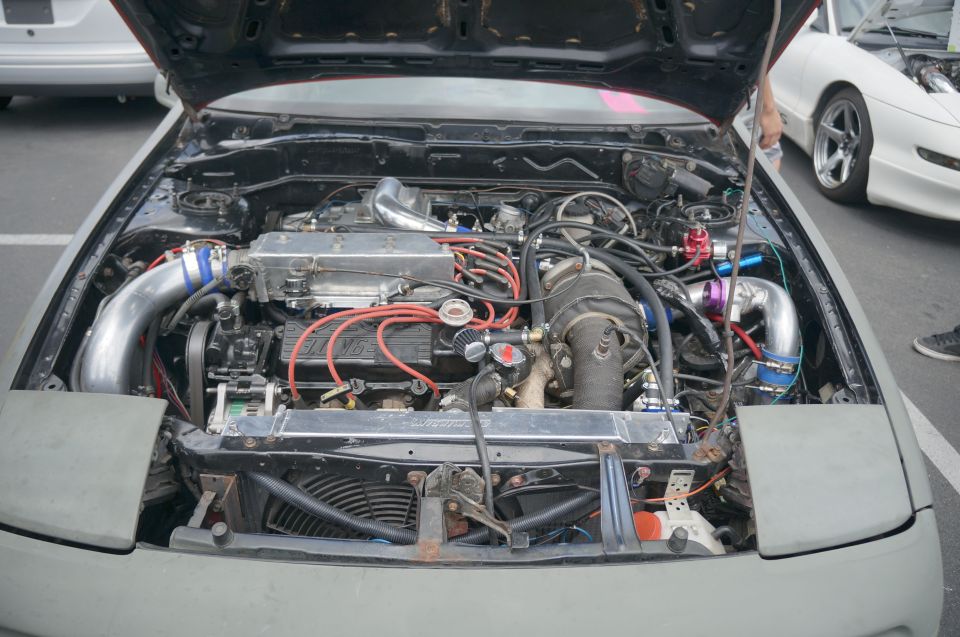 Engine bay with custom turbo setup and aftermarket intercooler. Gray car