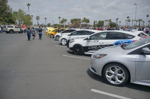 1995 Ford Taurus - Several cars are parked in a lot, including a white police car with 'Ford' branding.