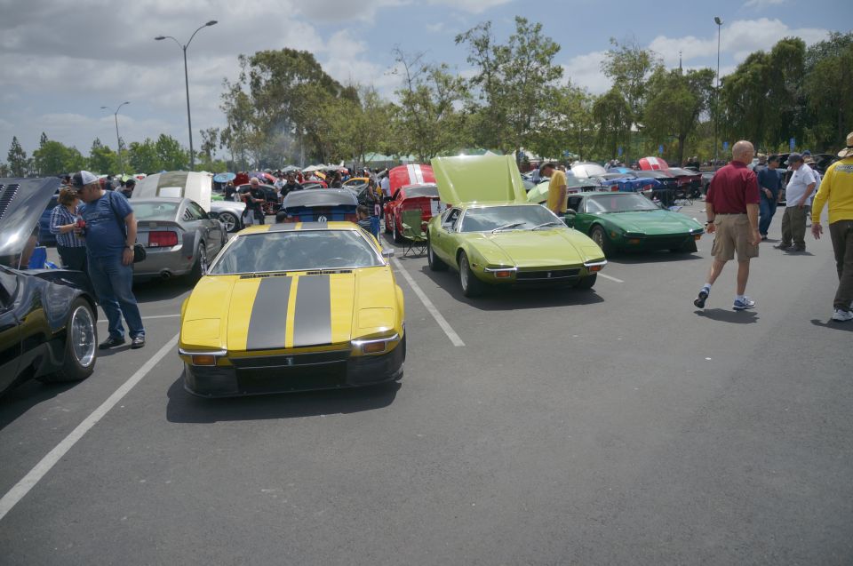 Yellow De Tomaso Pantera with dual grey racing stripes, front view, parked in a lot with other cars